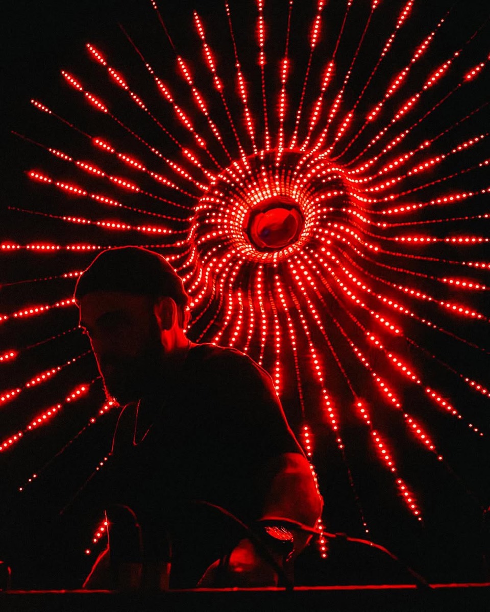 DJ silhouetted against a red audio-reactive LED spiral